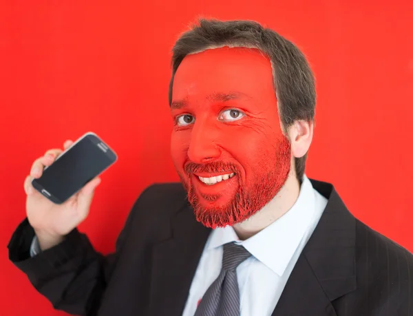 Young man portait with red painted face and smartphone — Stock Photo, Image