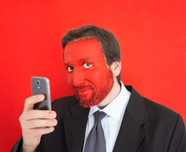 Jeune homme porte avec visage peint en rouge et smartphone — Photo