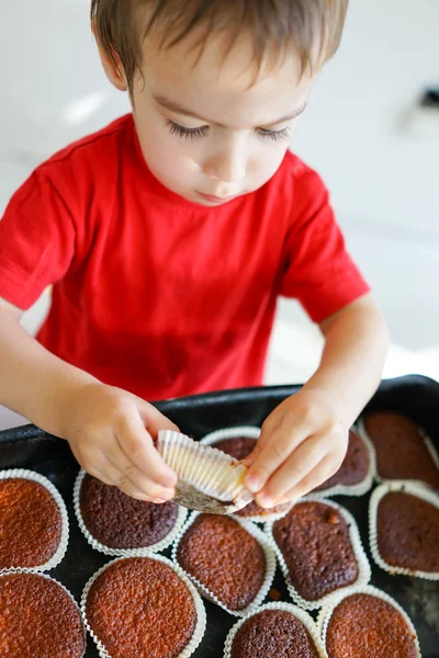 Roztomilé malé dítě jíst cupcakes doma — Stock fotografie