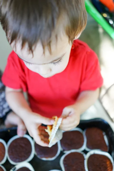 Χαριτωμένο μικρό παιδί που τρώει σπιτικά cupcakes Royalty Free Φωτογραφίες Αρχείου