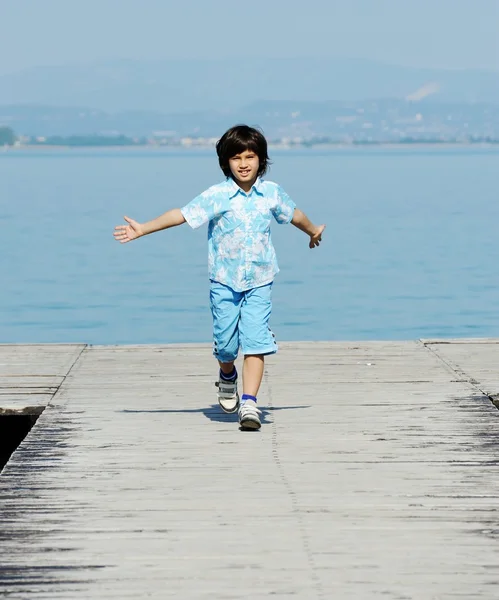 Niño corriendo y saltando en el muelle del mar —  Fotos de Stock