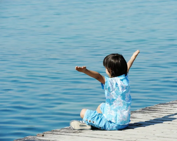 Niño por muelle de madera en un hermoso mar —  Fotos de Stock