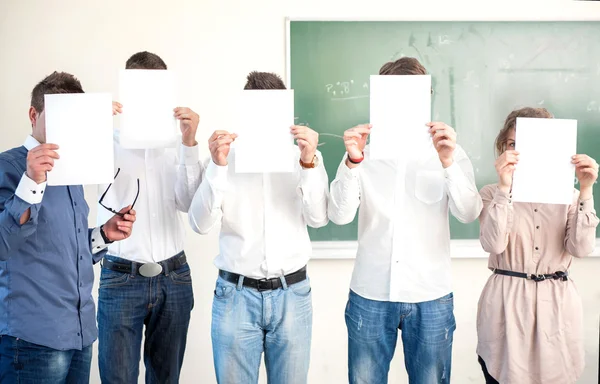 Studenti listů prázdného papíru před hlavy — Stock fotografie