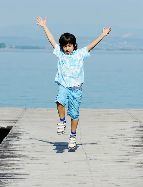 Bambino che corre e salta sul molo del mare — Foto Stock