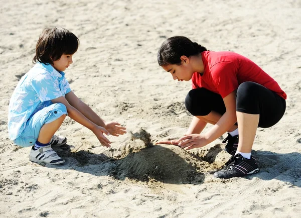 Barn på stranden leka med sand — Stockfoto