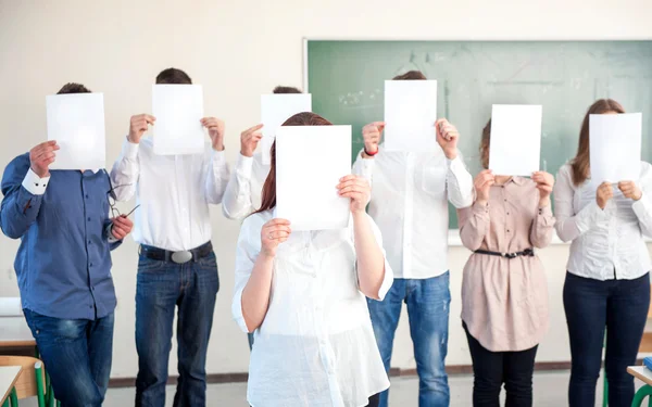 Studenti listů prázdného papíru před hlavy — Stock fotografie