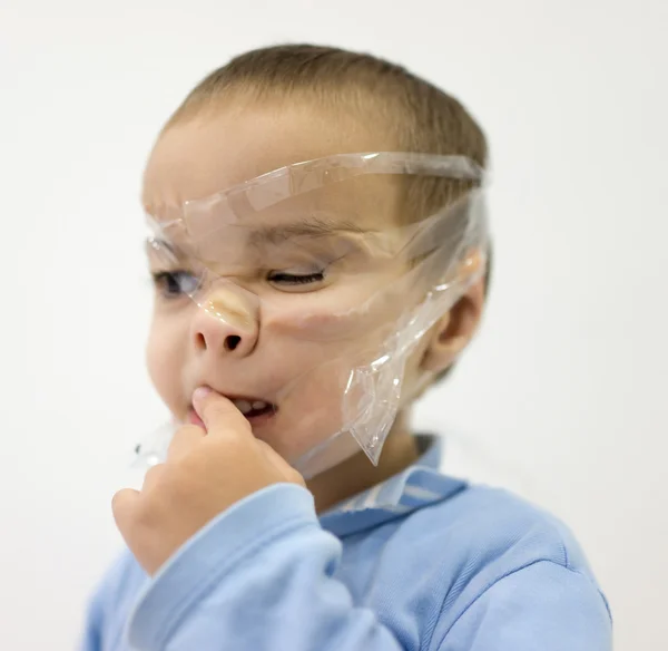 Divertido niño de dos años con cinta adhesiva en la cara — Foto de Stock