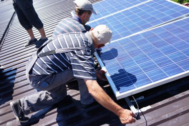 adam çatıda alternatif enerji fotovoltaik güneş panelleri yüklenmesi