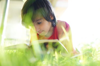 Çayır üzerine bir kitap okuma çocuk