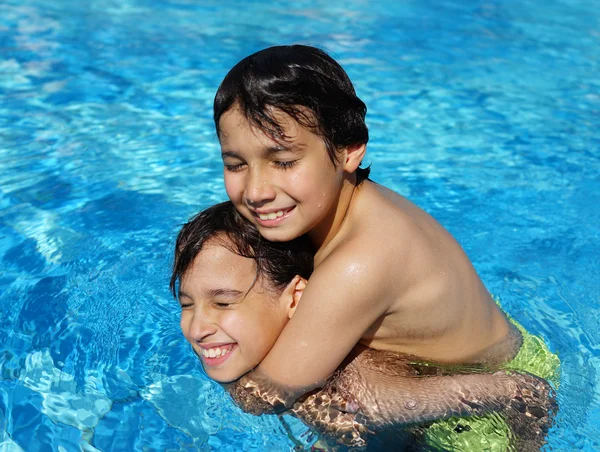 Happy kids enjoying in summer swimming pool — Stock Photo, Image