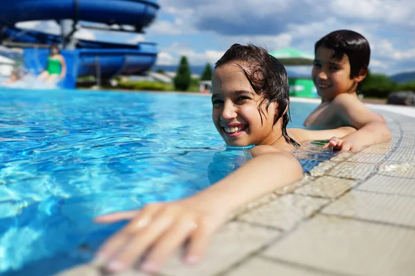 Glada barn njuter i sommar pool — Stockfoto