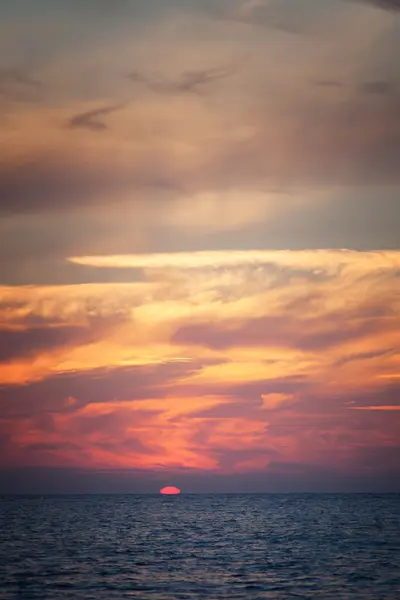 Sun falls through the clouds to the sea