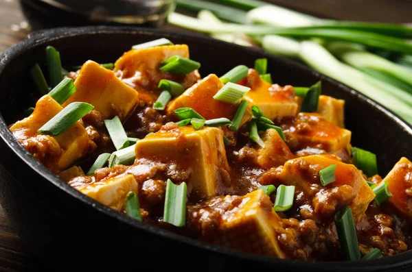 Mapo tofu in cast iron skillet with pork chopped chives soy sauce sichuan pepper garlic and spices