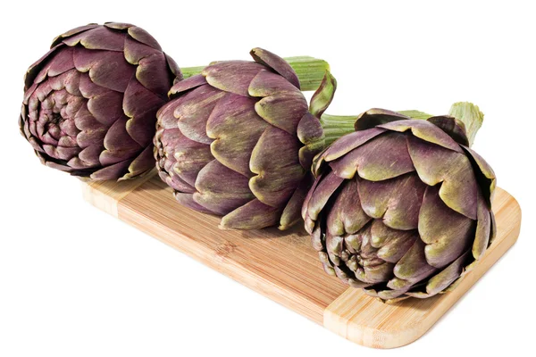 Three artichokes on a wooden plate — Stock Photo, Image