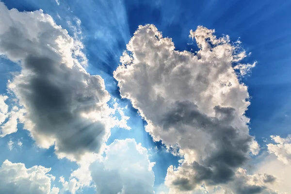 Blauer bewölkter Himmel mit Sonnenstrahlen — Stockfoto