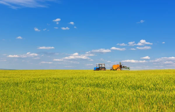 Farming traktor sprutning grönt fält — Stockfoto