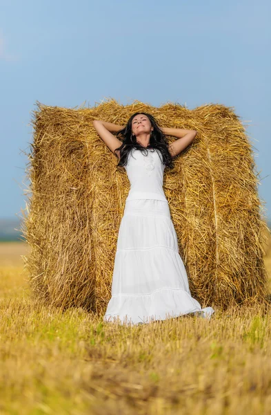 Brunette woman near hay bale — Stock Photo, Image