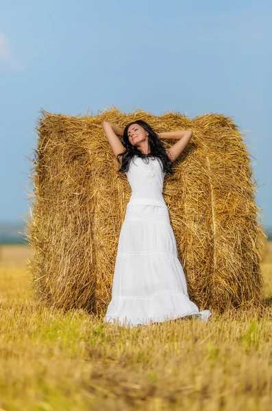 Brunette woman near hay bale — Stock Photo, Image