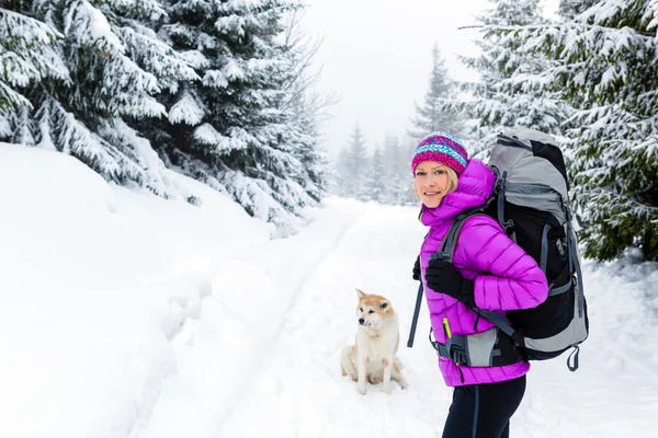 Mulher feliz andando na floresta de inverno com cão — Fotografia de Stock