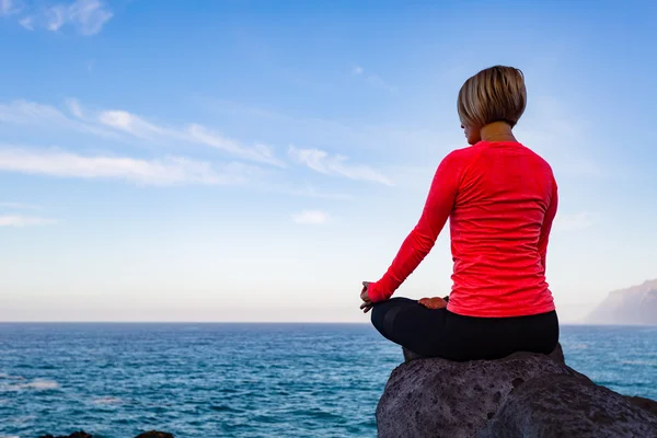 Femme méditant dans la pose de yoga, vue sur l'océan — Photo
