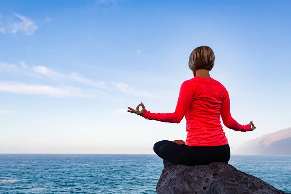 Femme méditant dans la pose de yoga, vue sur l'océan — Photo