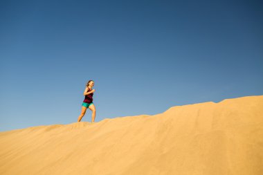 Genç kadın kum çöl dunes üzerinde çalışan