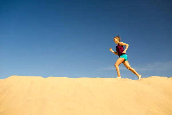 Fiatal nő fut a homokos sivatagi dűnék — Stock Fotó