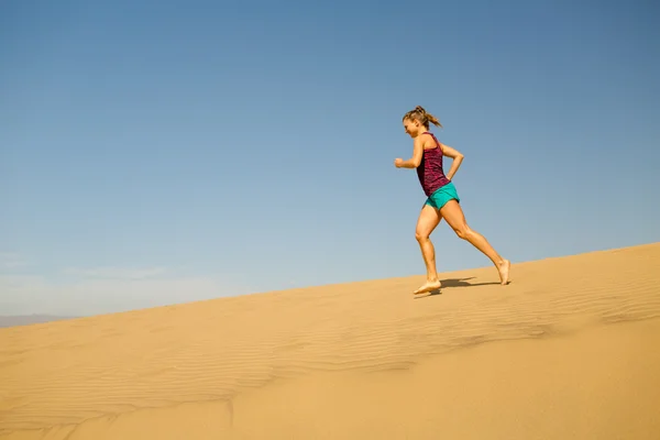 Młoda kobieta działa na piasek pustyni wydmy — Zdjęcie stockowe
