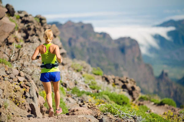 Mujer joven corriendo en las montañas en el día de verano — Foto de Stock