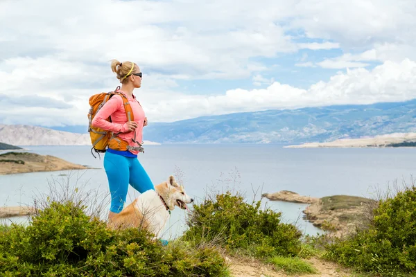 Kadın köpekle sahil izinde yürüyen hiking — Stok fotoğraf