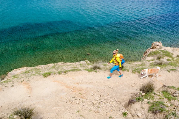 Kadın köpekle sahil izinde yürüyen hiking — Stok fotoğraf