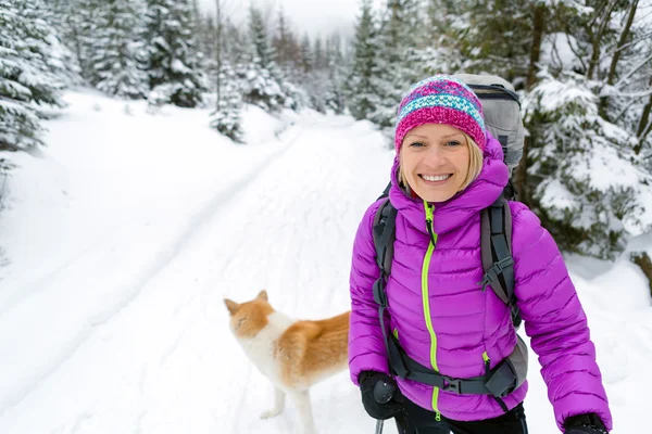 Donna felice che cammina nella foresta invernale con cane — Foto Stock