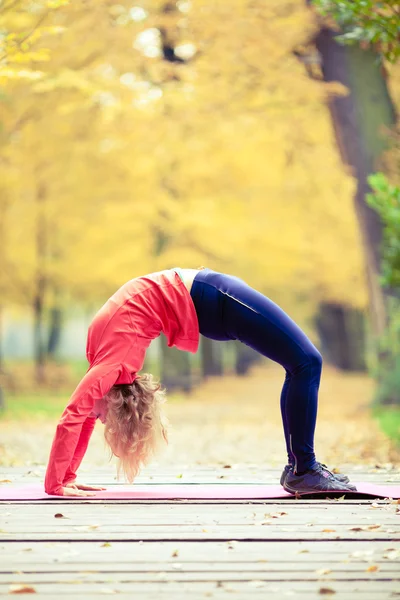 Happy young woman doing yoga in park — Stock Photo, Image