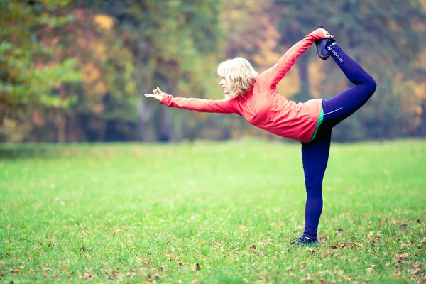 Mutlu genç kadın parkta yoga yapıyor — Stok fotoğraf
