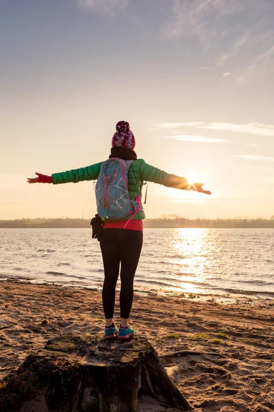 Mulher caminhante com braços estendidos desfrutar do nascer do sol no lago — Fotografia de Stock