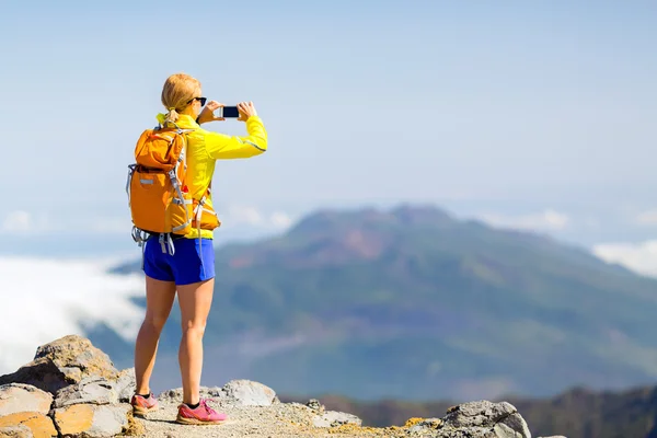 Mujer excursionista tomando fotos en las montañas — Foto de Stock