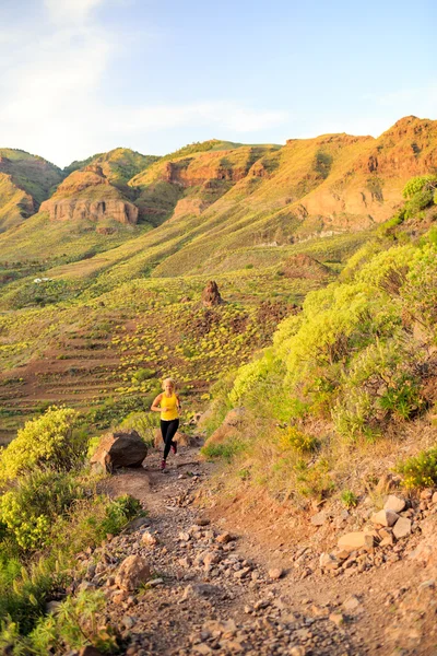 Donna che corre in montagne rocciose al tramonto estivo — Foto Stock