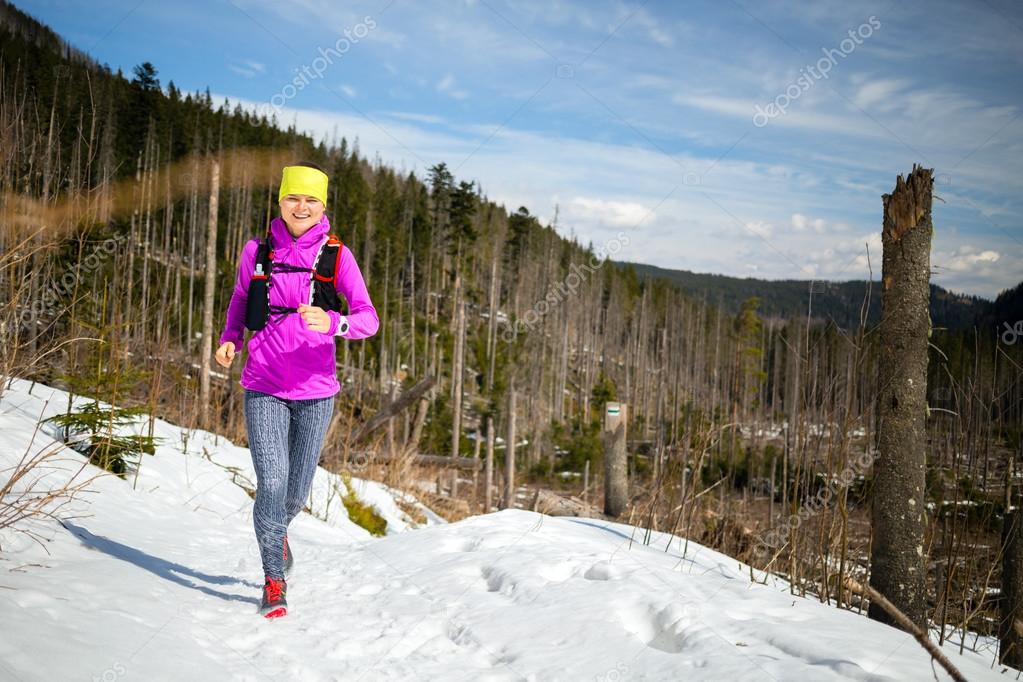 Woman winter trail running in mountains on snow