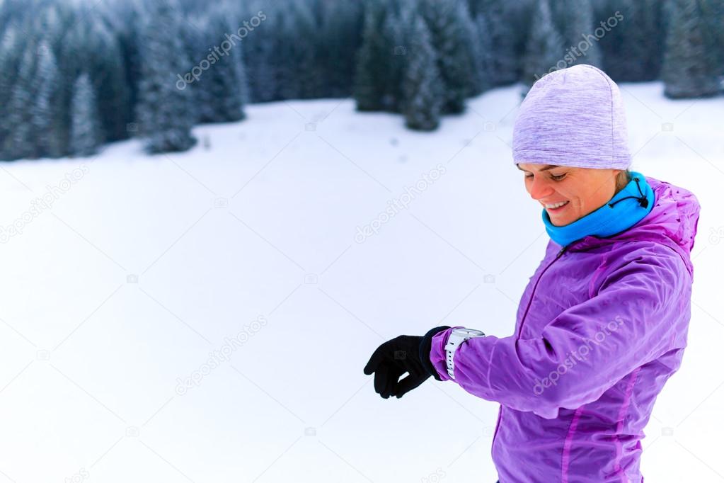 Woman runner checking sports watch on winter run