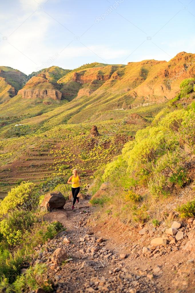 Woman running in rocky mountains on summer sunset