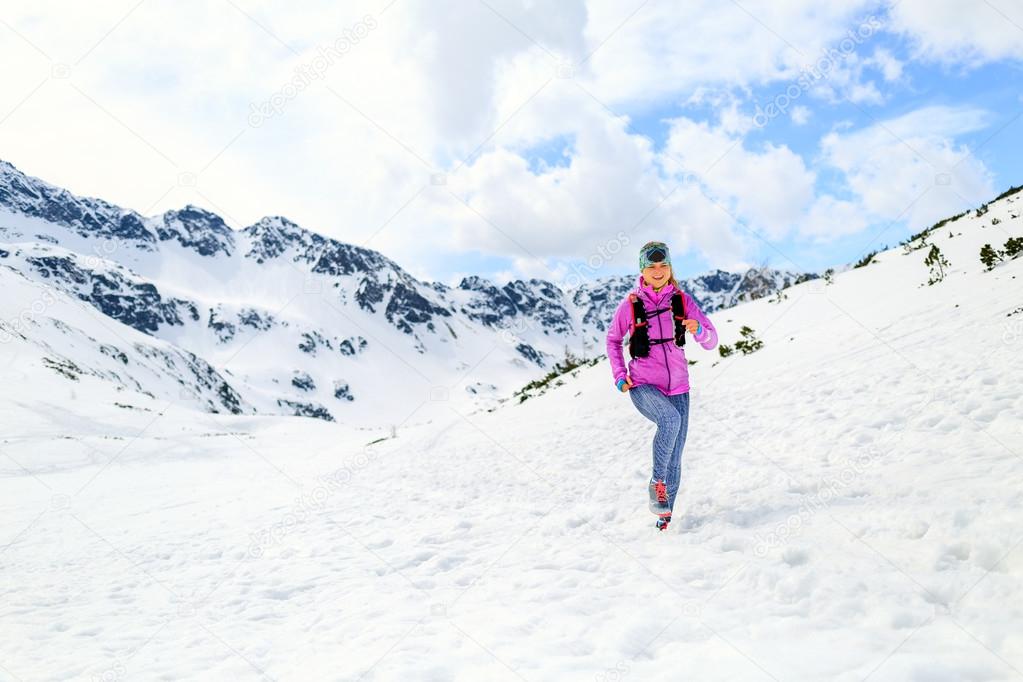 Woman running in mountains in inspirational winter landscape