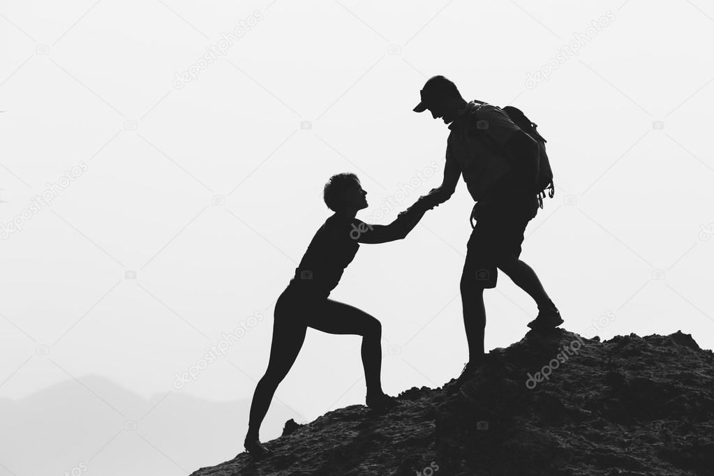 Teamwork couple hiking climbing helping hand