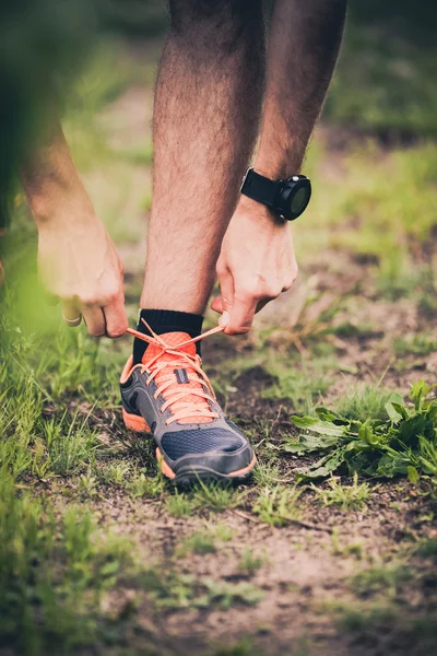 Runner tying sports shoe on trail — Stockfoto