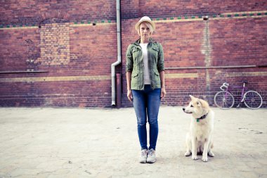 Hipster woman with dog and vintage road bike in city clipart