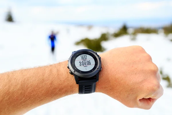 Runner on mountain winter trail looking at stopwatch, activity m — Stock Photo, Image