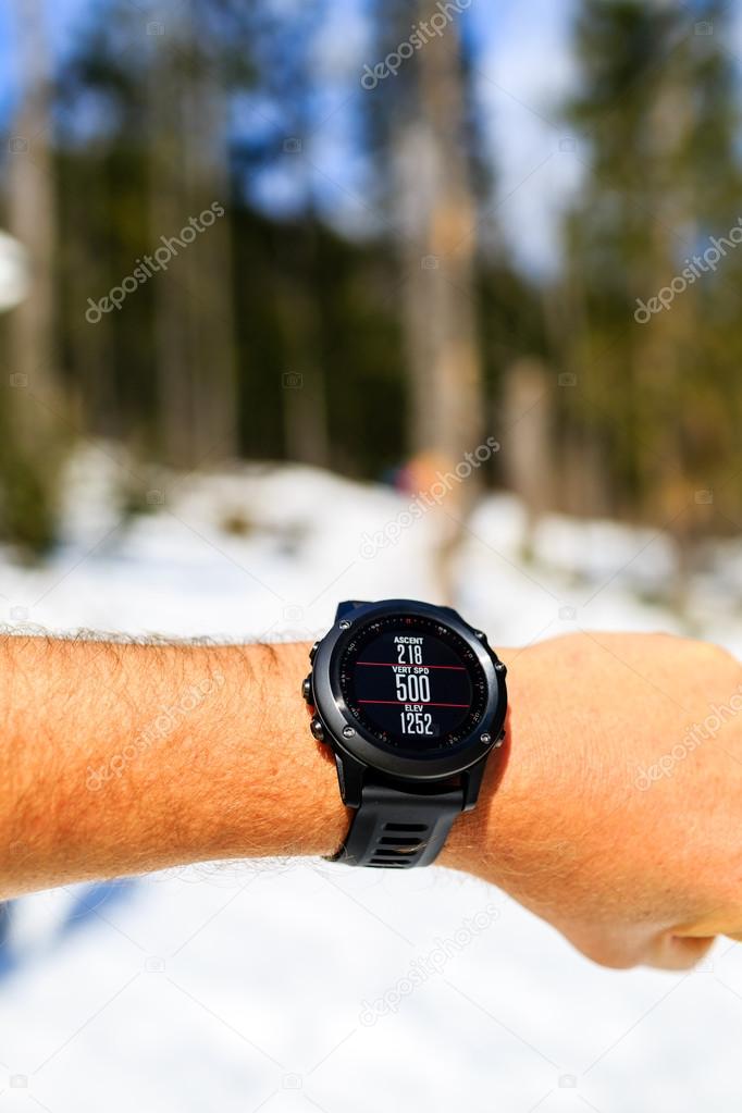 Runner on mountain trail looking at stopwatch, activity tracker