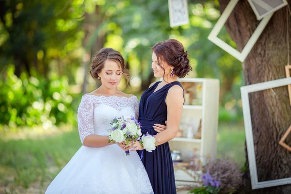 Красивая невеста с подружкой невесты в саду — стоковое фото