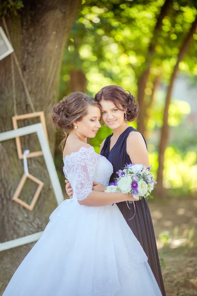 Bela noiva com dama de honra no jardim — Fotografia de Stock