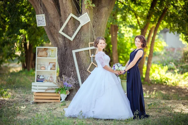 Schöne Braut mit Brautjungfer im Garten — Stockfoto
