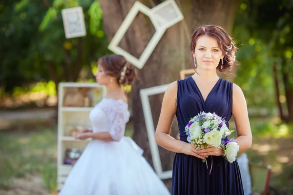 Gyönyörű menyasszony a koszorúslány a kertben — Stock Fotó